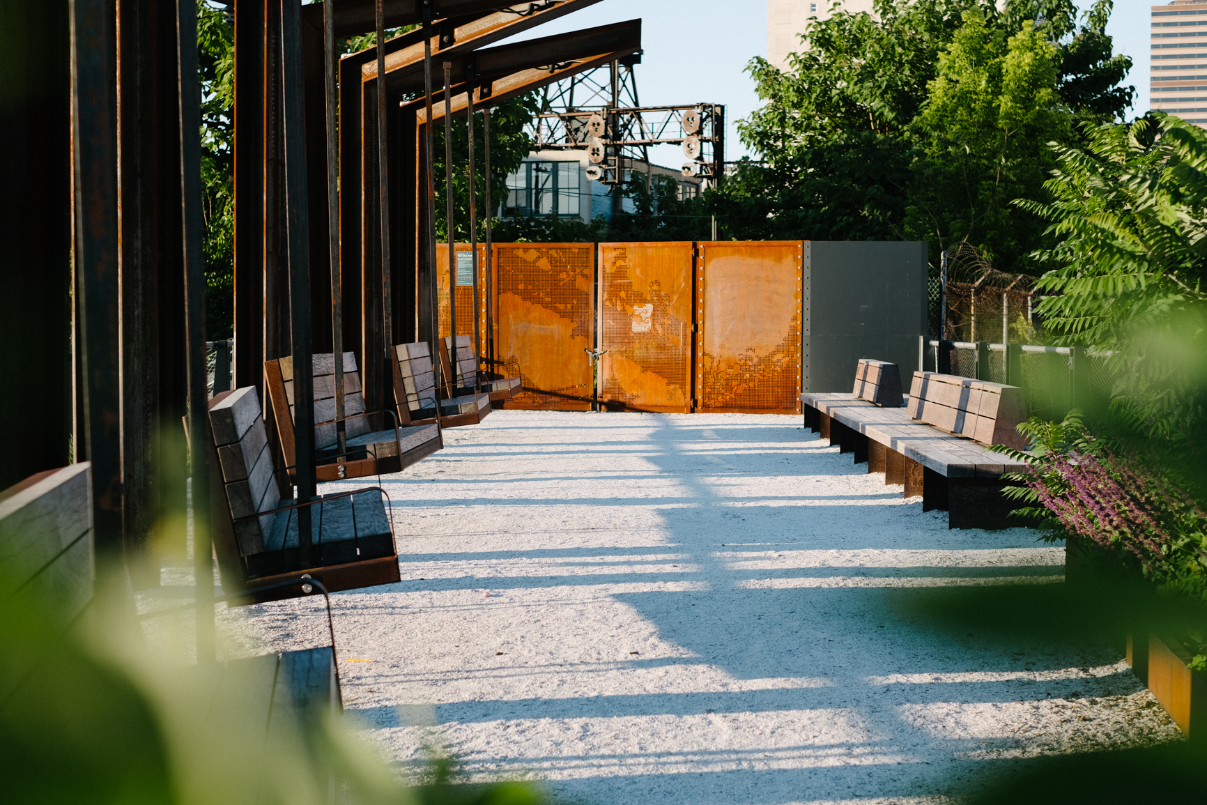 Wooden benches along the sides of a path. The path has green trees on the perimeter.